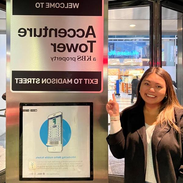 Daniella Soriano pointing to an Accenture Tower sign